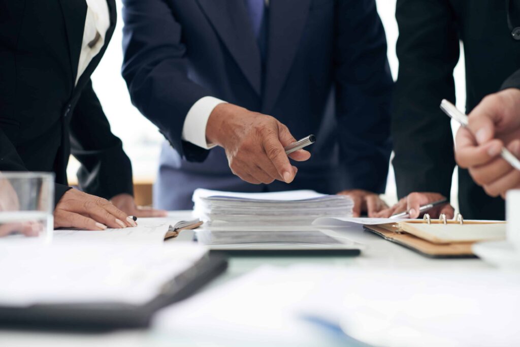 Lawyers in business suits reviewing legal documents and contracts during a meeting in a law office. Lawyers in business suits reviewing legal documents and contracts during a meeting in a law office.